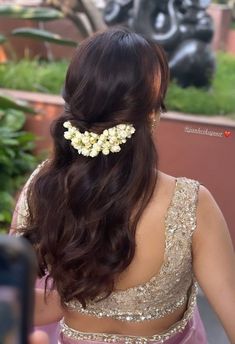 the back of a woman's head with flowers in her hair, wearing a purple dress