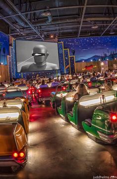 a large group of cars with people in the back seats watching a movie on a big screen