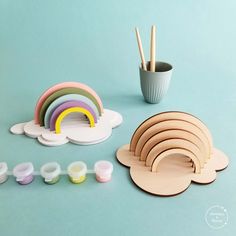 a set of wooden toys including paints, paintbrushes and rainbows on a blue background