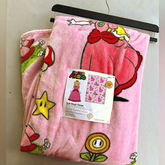 a pink blanket with pictures of princesses and stars on it hanging from a wall