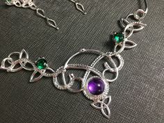 I've fabricated a Celtic Knot statement neck ring, in 925 sterling silver, and I will set your choice of an 8mm cabochon gemstone within the drop down menu. For perspective, I've shown this with amethyst, but you can choose from a varied selection if you prefer. I've made the choker approximately 14.5-15 inches but please specify if you need it longer or shorter as I will accommodate. Also, included will be two, 5mm emerald faceted gems to compliment the piece. If you prefer another color, pleas Handmade Silver Custom Necklace For Formal Events, Handmade Sterling Silver Necklace For Wedding, Silver Hallmarked Custom Necklace For Wedding, Sterling Silver Jewelry With Unique Variations For Gifting, Unique Sterling Silver Jewelry As Gift, Handmade Adjustable Silver Custom Necklace, Green Sterling Silver Jewelry With Intricate Design, Silver Birthstone Jewelry For Jewelry Making, Unique Silver Jewelry With Birthstone