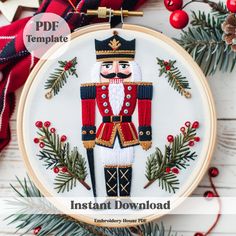 an embroidered christmas ornament with a nutcracker on it and pine branches