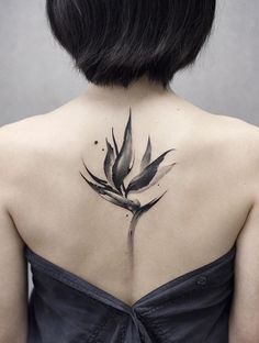 the back of a woman's neck with a bird of paradise tattoo on it