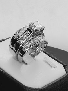 a couple of rings sitting on top of a black and white ring box with some diamonds