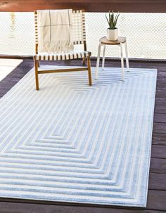 a chair sitting on top of a wooden floor next to a white and blue rug