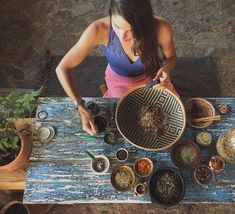 a woman sitting at a table with many bowls and spoons on top of it