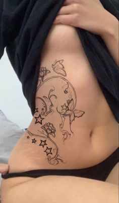 a woman's stomach with tattoos on it and stars around the bottom part of her belly