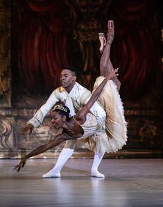 two ballerinas performing on stage with one holding the other