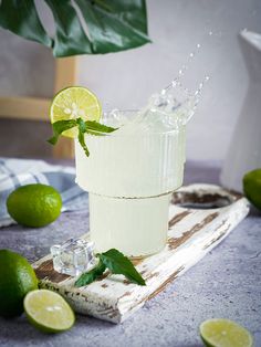 a glass filled with ice and limes on top of a table