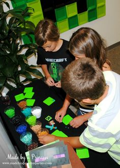 two young boys playing with green and black tiles on a table in front of a plant