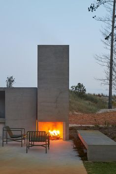 two chairs sitting in front of a fire place with an open door on the side