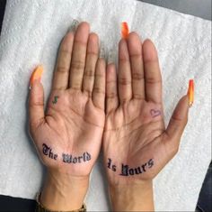 two hands with the words the world is yours written on their palms, and an orange nail polish