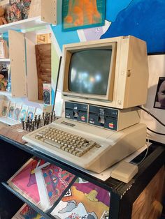 an old computer sitting on top of a desk next to books and other items in front of it