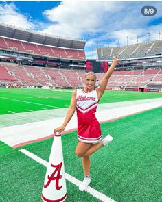 a woman in a cheerleader uniform standing next to a cone at a football stadium