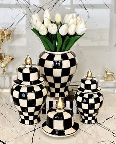 black and white checkered vases with tulips in them on a marble table