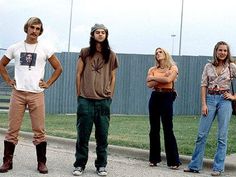 four people standing in the street with their arms crossed and one person wearing cowboy boots