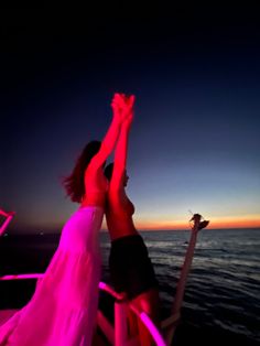 two women on a boat reaching up into the sky