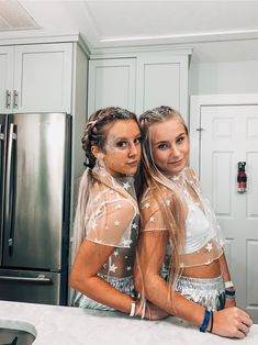 two young women dressed in costumes standing next to each other at a kitchen counter top