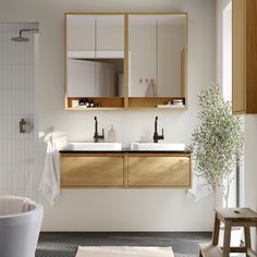 a bathroom with two sinks, mirrors and a bathtub