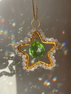 a star ornament hanging from a string with a green crystal in the center