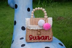 a straw purse with pom - poms on it sitting on top of a blue bench