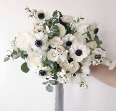 a vase filled with white flowers and greenery