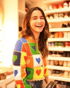 a smiling woman holding a skateboard in front of a store shelf filled with shoes