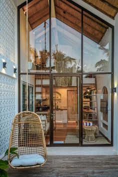 the inside of a house with glass walls and wooden flooring, including a hanging chair