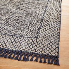 a blue and white rug with tassels on the bottom is laying on a wooden floor