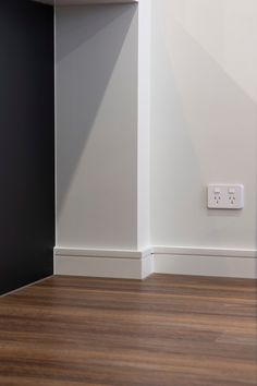 an empty room with white walls and wood flooring is pictured in this image, there are two electrical outlets on the wall