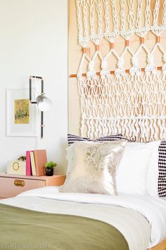 a bed with white sheets and pillows on top of it next to a wall hanging