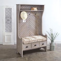 a wooden bench with two drawers and a hat rack on the wall above it, next to a potted plant