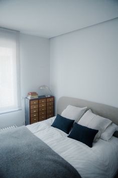 a bedroom with a bed, dresser and window