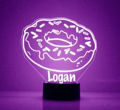 a lit up doughnut sitting on top of a wooden stand in front of a purple wall