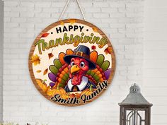 a happy thanksgiving sign with a turkey wearing a pilgrim hat hanging on a brick wall