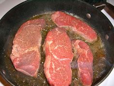 some meat is cooking in a skillet on the stove top with colorful circles around it