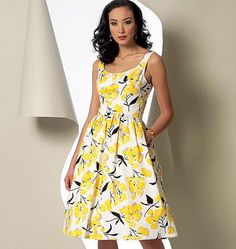 a woman standing in front of a white wall wearing a yellow and black floral dress