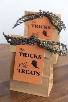 two halloween treat bags sitting on top of a wooden table