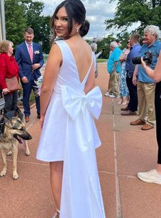 a woman in a white dress standing next to a dog