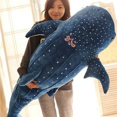 a woman holding a stuffed whale in her arms