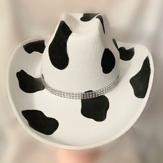 Black Cowprint with Rhinestone Band Cowboy Hat. This cowboy hat is the perfect addition to your party, events, and even cute photos! This is an adult-sized, polyester cowboy hat hand-painted with a double rhinestone band. The cowprint is only on the top of the hat. The bottom of the hat is white. The hat circumference is 23 inches. Keep in mind that this is not a fitted cowboy hat, one size fits most but it ranges on the larger size. We hope you will love this stunning hat as much as we do! You Painted Cowboy Hats Ideas, Personalized Cowboy Hat, Sombrero Vaquero Aesthetic, Sombreros Aesthetic, Cowboy Hat Ideas, Decorated Cowboy Hats, Cow Girl Hats, Cow Boy Hats, Cowboy Hat Painting