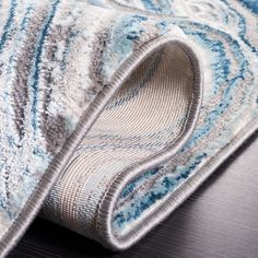 a close up view of a blue and white rug on a wooden floor with a black table in the background