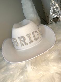 Bring your best self out for the world to see with this simple design Bride hat. Grab this Adorable White Cowboy style Hat! Featuring BRIDE in silver and pearl decorations. This Western style novelty hat is so fun! It is perfect for Night or a Bachelorette Party! Sized approximately 62 cm, it's great for both Men and Women! Wear it on your Wedding Day! Stylish and bedazzling, this Country Style hat is great for Rodeo style weddings, bridal shower supplies, and more!  The cute hat is lightweight and made of soft polyester. Spot clean only. Silver Wide Brim Costume Hat With Adjustable Fit, Silver Wide Brim Adjustable Costume Hat, Silver Adjustable Wide Brim Costume Hat, Adjustable Silver Fedora Hat, Adjustable Silver Mini Hat With Wide Brim, Adjustable Wide Brim Silver Mini Hat, White Wide Brim Hat For Gift, White Wide Brim Hat As Gift, Customizable Adjustable Party Hats