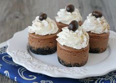 mini chocolate cheesecakes with whipped cream and chocolate topping on a white platter