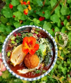 a bowl filled with food and garnish on top of green plants in the background