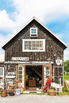 an old wooden building with lots of windows and furniture in it's front door