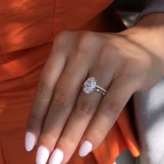 a close up of a person's hand with a ring on her finger and an orange dress