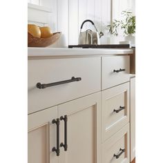 an image of a kitchen setting with white cupboards and black pulls on the handles