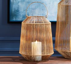 two wicker lanterns sitting next to each other on a wooden floor in front of a blue wall