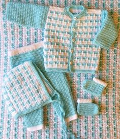 a crocheted baby sweater and booties is shown on a bed with matching blankets